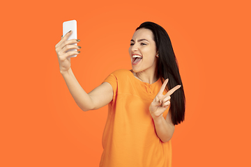 Image showing Caucasian young woman\'s portrait on orange background