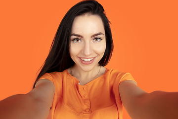 Image showing Caucasian young woman\'s portrait on orange background