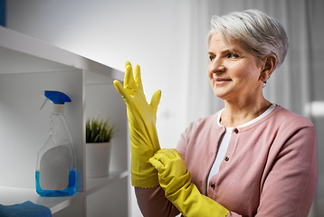 Image showing senior woman putting protective rubber gloves on