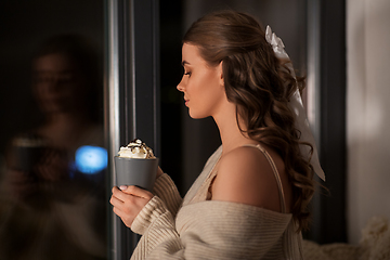 Image showing woman holding mug with whipped cream at night