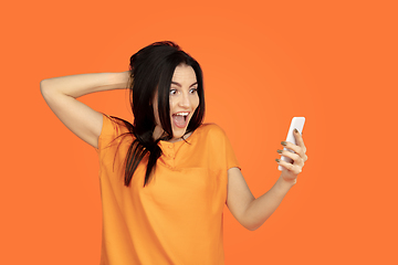 Image showing Caucasian young woman\'s portrait on orange background