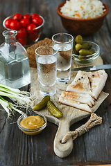 Image showing Vodka and traditional snack on wooden background