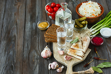 Image showing Vodka and traditional snack on wooden background