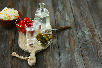 Image showing Vodka and traditional snack on wooden background