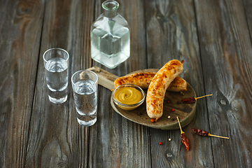 Image showing Vodka and traditional snack on wooden background