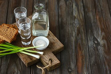 Image showing Vodka and traditional snack on wooden background