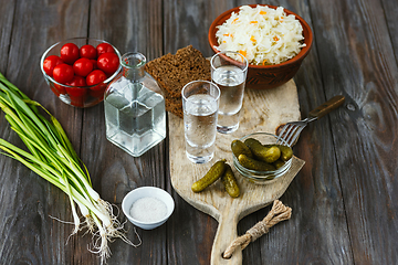 Image showing Vodka and traditional snack on wooden background