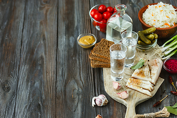 Image showing Vodka and traditional snack on wooden background