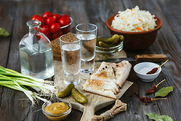 Image showing Vodka and traditional snack on wooden background