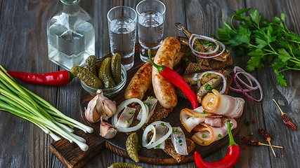 Image showing Vodka and traditional snack on wooden background