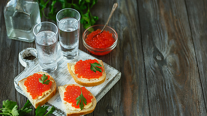 Image showing Vodka and traditional snack on wooden background