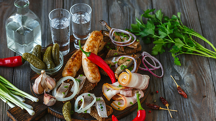 Image showing Vodka and traditional snack on wooden background