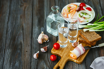 Image showing Vodka and traditional snack on wooden background