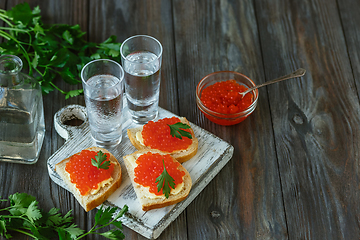 Image showing Vodka and traditional snack on wooden background