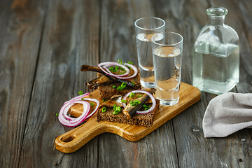 Image showing Vodka and traditional snack on wooden background