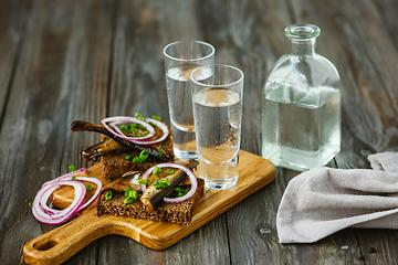 Image showing Vodka and traditional snack on wooden background