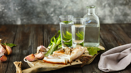 Image showing Vodka and traditional snack on wooden background