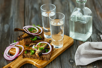 Image showing Vodka and traditional snack on wooden background