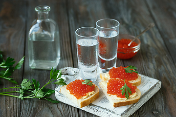 Image showing Vodka and traditional snack on wooden background