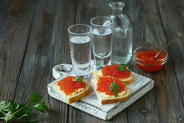 Image showing Vodka and traditional snack on wooden background