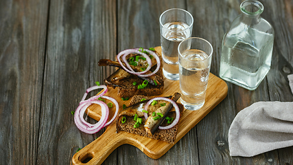 Image showing Vodka and traditional snack on wooden background