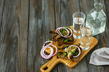 Image showing Vodka and traditional snack on wooden background