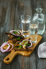 Image showing Vodka and traditional snack on wooden background