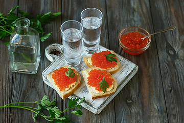 Image showing Vodka and traditional snack on wooden background