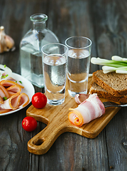 Image showing Vodka and traditional snack on wooden background