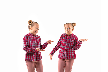 Image showing Young handsome girl arguing with herself on white studio background.