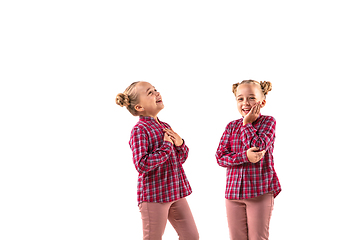 Image showing Young handsome girl arguing with herself on white studio background.