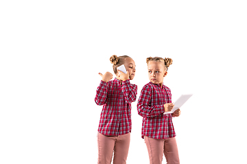 Image showing Young handsome girl arguing with herself on white studio background.