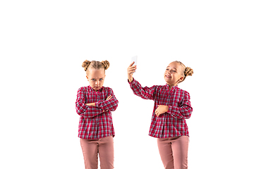 Image showing Young handsome girl arguing with herself on white studio background.