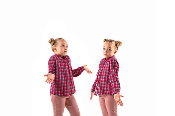 Image showing Young handsome girl arguing with herself on white studio background.