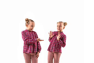 Image showing Young handsome girl arguing with herself on white studio background.