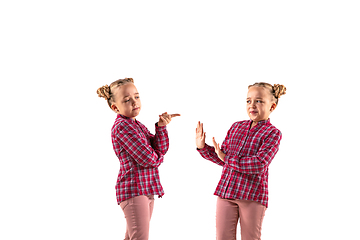 Image showing Young handsome girl arguing with herself on white studio background.