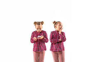 Image showing Young handsome girl arguing with herself on white studio background.