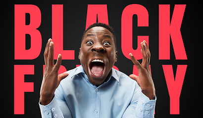 Image showing Half-length close up portrait of young man on black background with black friday lettering