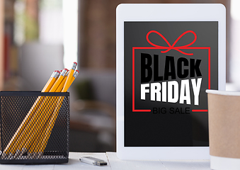 Image showing Front view of tablet and office accessories with black friday lettering on blurred background
