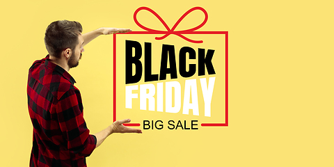 Image showing Half-length close up portrait of young man on yellow background with black friday lettering