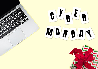 Image showing Top view of laptop and present, gift with cyber monday lettering on yellow background