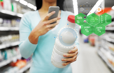 Image showing woman with smartphone buying milk at supermarket