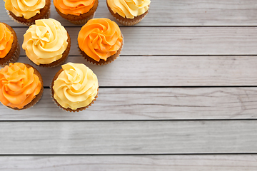 Image showing cupcakes with frosting on wooden boards background