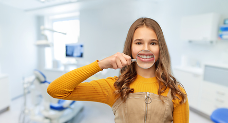 Image showing girl with magnifier shows teeth at dental clinic