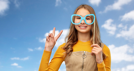 Image showing smiling teenage girl with big glasses over sky