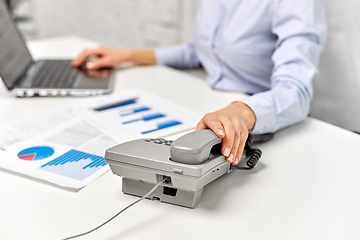 Image showing businesswoman calling on desk phone at office