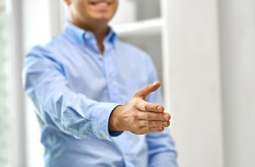 Image showing smiling businessman making handshake at office