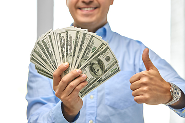 Image showing smiling businessman with money showing thumbs up