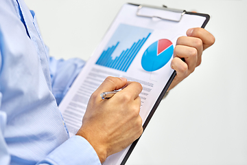 Image showing hands of businessman holding clipboard with charts