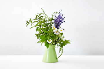 Image showing bunch of herbs and flowers in green jug on table